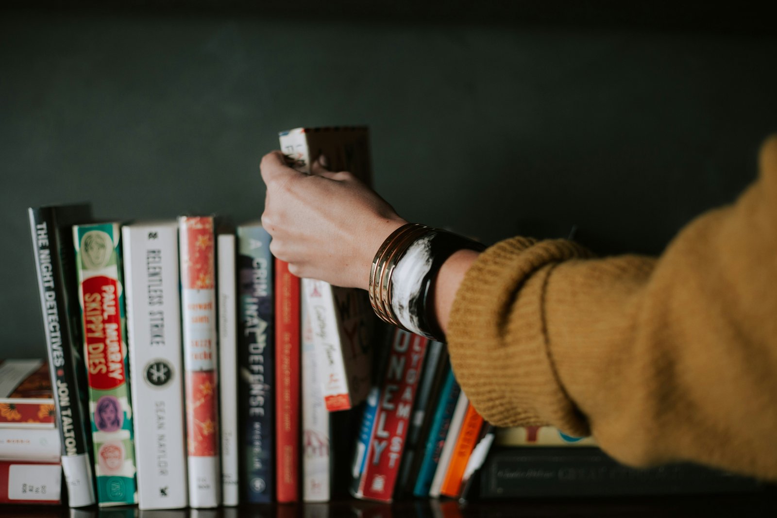 A hand taking a book from the shelf